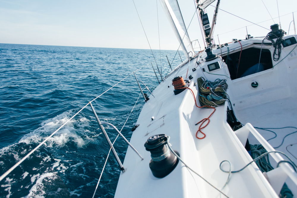 deck professional sailboat racing yacht during competition sunny windy summer day moving fast through waves water with spinnaker up